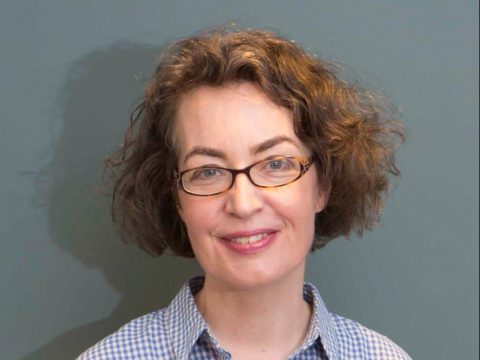 Kate Clanchy with short curly hair and glasses looking to camera.