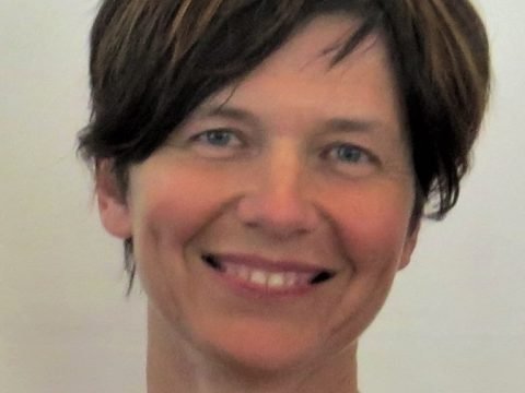 Sharon Black smiling against a white wall.