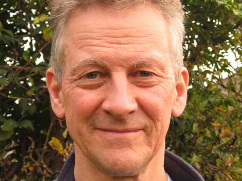 Head shot of Iain Macrath standing in front of trees.