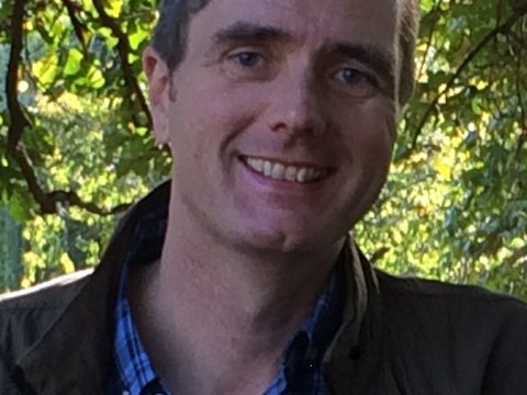 Alasdair Campbell standing in front of trees